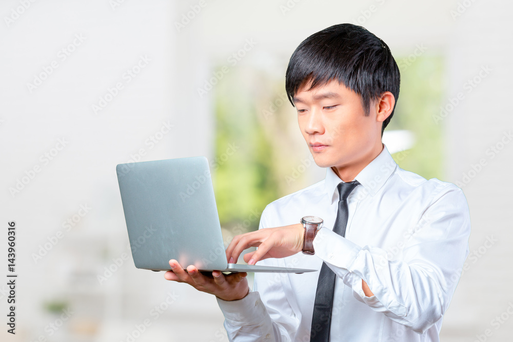 young smiling asian businessman holding laptop young smiling asian businessman holding laptop