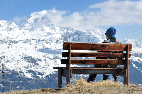 homme assis sur un banc contemplant la montagne
