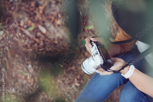 Woman looking at camera's monitor checking pictures taken.