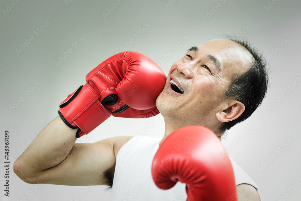 Portrait of Asian senior man punching his face with red boxing gloves on white background. Failure, Mistake, bankrupt, Losing concepts. Portrait of Asian senior man punching his face with red boxing gloves on white background. Failure, Mistake, bankrupt, Losing concepts.