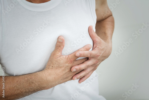 Senior man having heart attack while working out on white background at the gym. copy space.