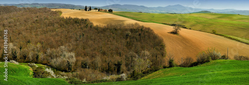 Tuscany landscape with green fields, blooming trees and little chapel of Madonna di Vitaleta, San Quirico d'Orcia, Siena, Italy