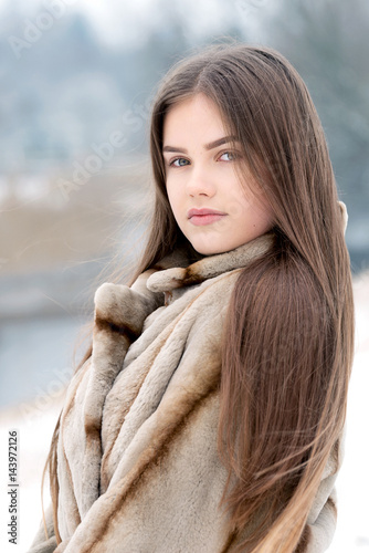 Teenager girl in the snow with fur coat