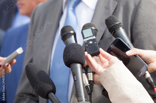 Media interview with business person. Press conference. Microphones.