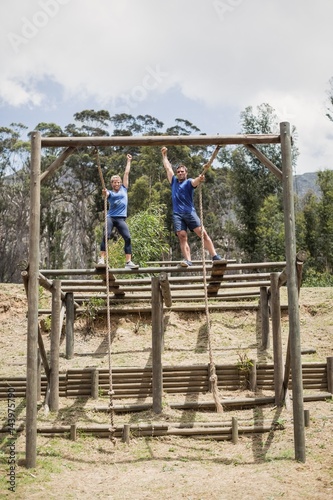 Fit man and woman climbing down the rope during obstacle course