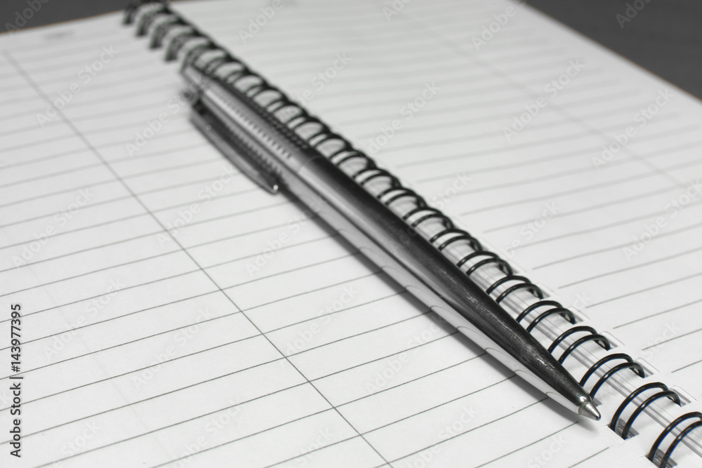 Metallic ball pen on office spiral notebook (manual focus on the pen tip) close up Metallic ball pen on office spiral notebook (manual focus on the pen tip) close up
