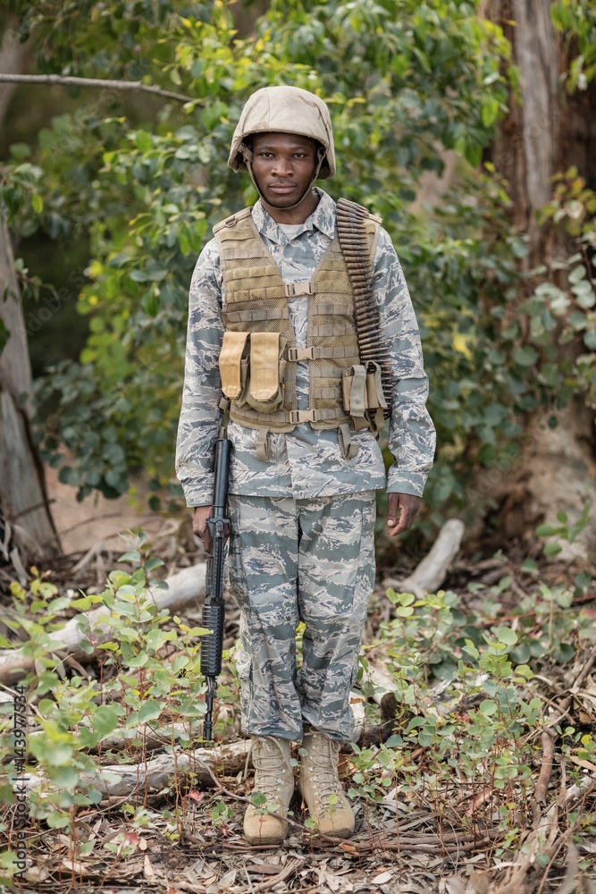 Portrait of confident military soldier standing with rifle