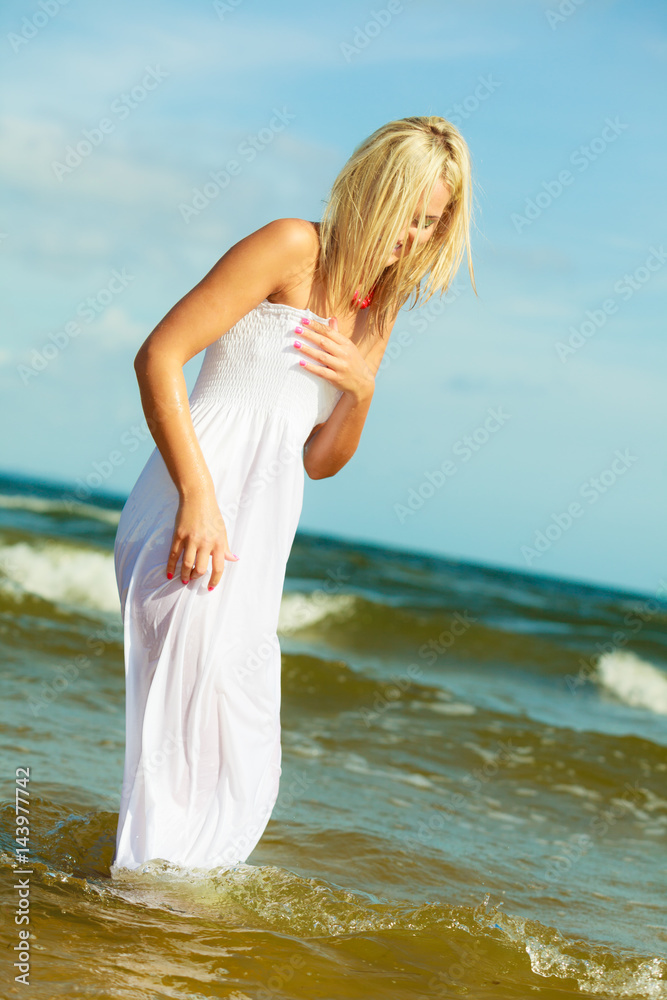 Blonde woman wearing dress walking in water Blonde woman wearing dress walking in water