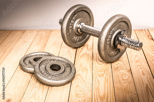 Dumbbells , weight plates on wooden background for bodybuilder. Concept for sport player or workout. gym of accessories for fitness