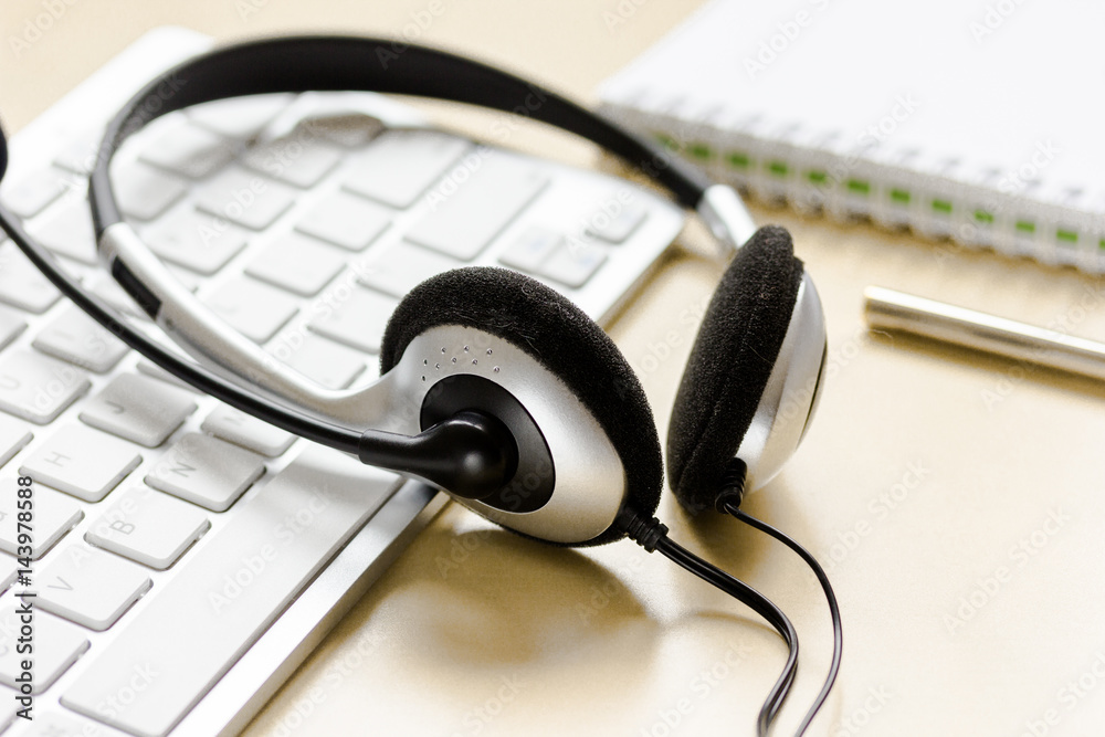 Office desk with headset and keyboard brown background Office desk with headset and keyboard brown background