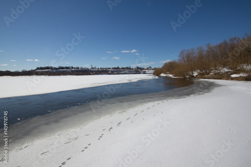 The river is covered with melting ice on a sunny spring day