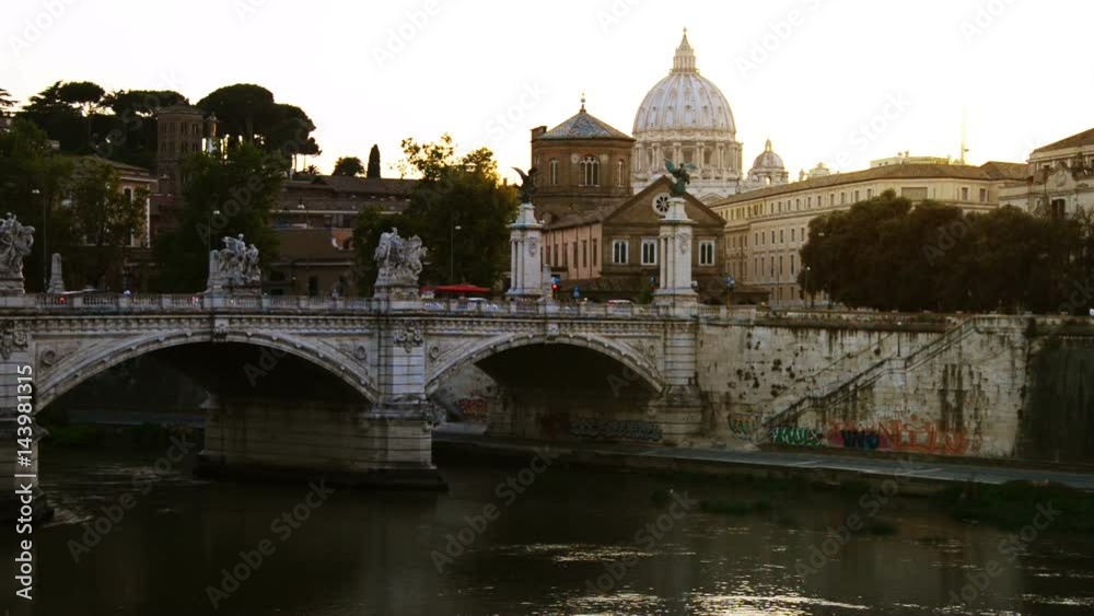 Rome, Italy. View of St. Peters Basilica in Vatican City with Vittorio Emanuele II bridge. Sunset with bright sky. River reflection, graffiti on the wall Rome, Italy. View of St. Peters Basilica in Vatican City with Vittorio Emanuele II bridge. Sunset with bright sky. River reflection, graffiti on the wall