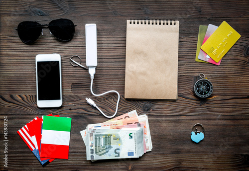 Preparation for traveling with cash and mobile on wooden background top view