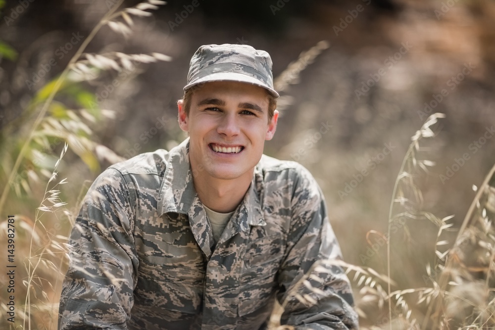 Portrait of happy military soldier crouching in grass