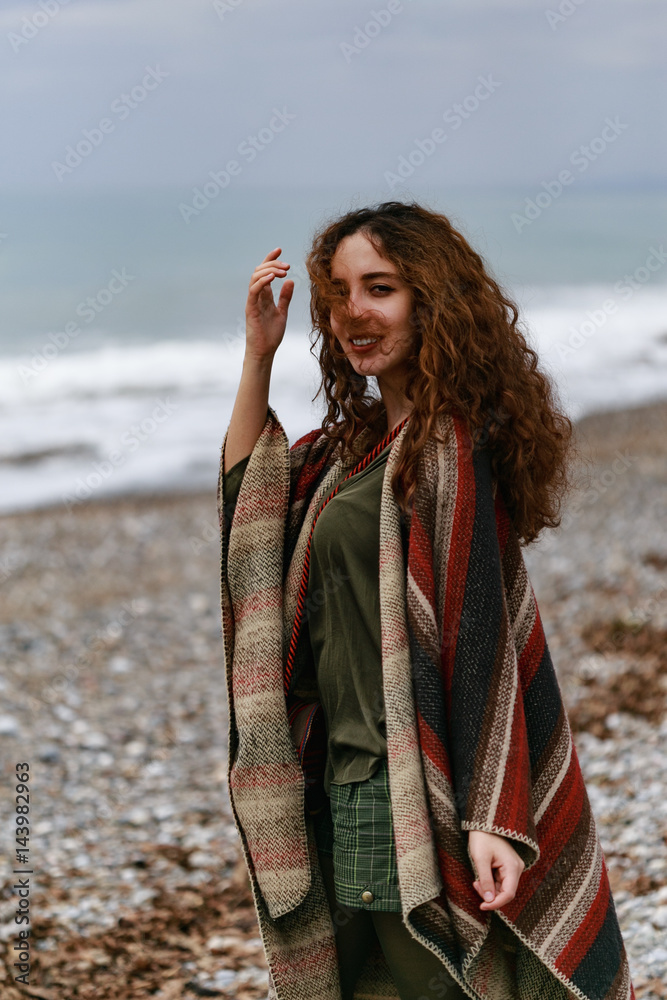 Portrait of happy brunette woman on the beach wearing poncho Portrait of happy brunette woman on the beach wearing poncho