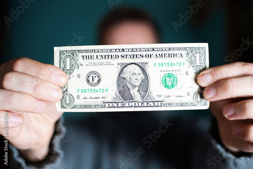 A man holds a U.S. 1 one dollar
