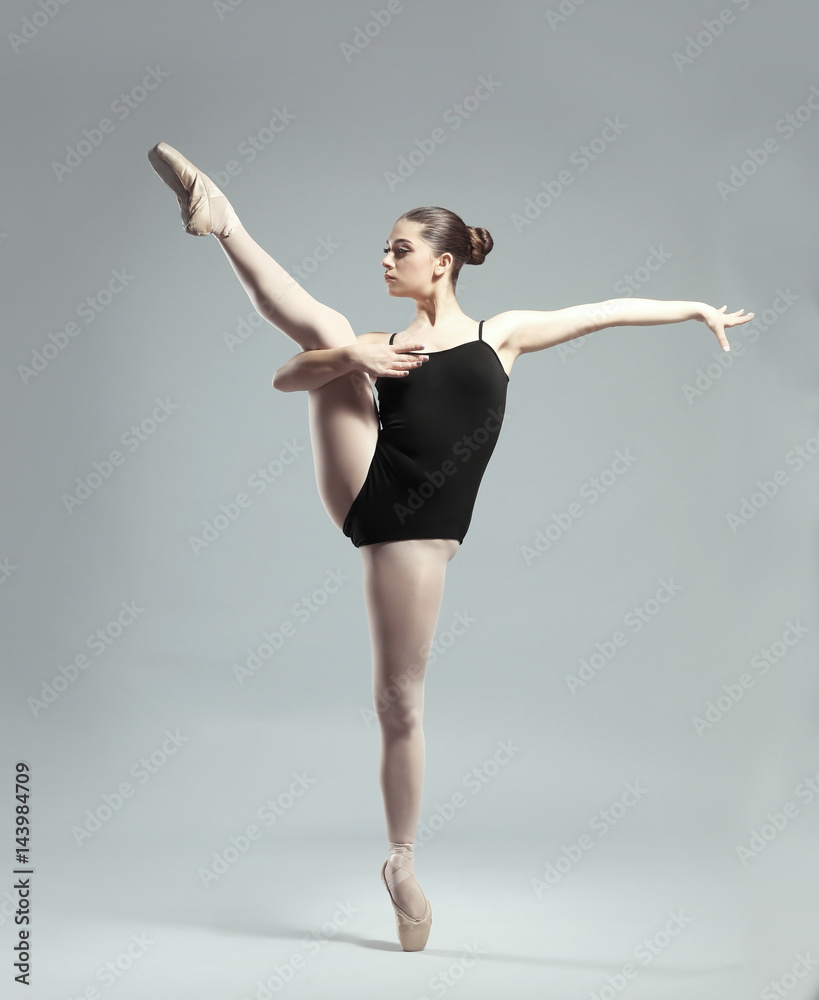 Fototapeta premium Young beautiful ballerina dancing on light background