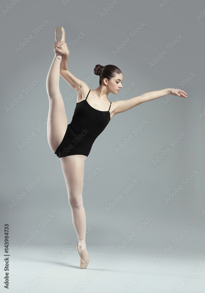 Fototapeta premium Young beautiful ballerina dancing on light background
