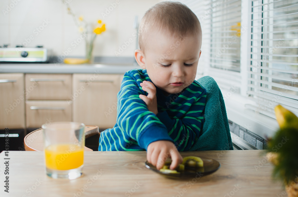 the child in the kitchen with juice and kiwi the child in the kitchen with juice and kiwi