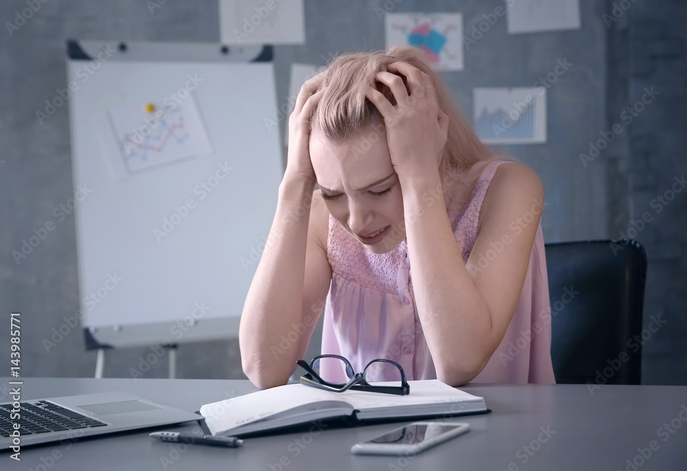 Beautiful young woman suffering from headache while working in office