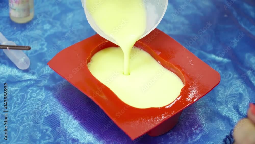 Hands pouring soap base to the red template