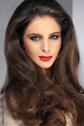 A beauty image of a brunette model with perfect skin and beautiful red lips