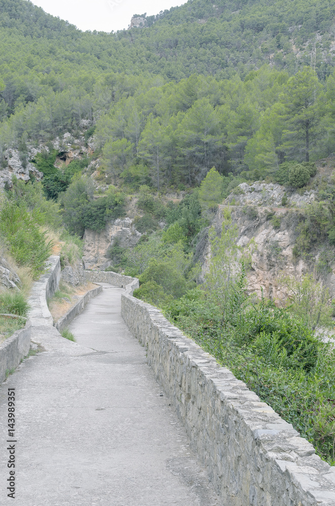 Path to Spring of bathes, near to the thermal village of Montanejos, iside the province of Castellon (Valencia - Spain). Mountain landscape. Green environment. Cloudy day. Path to Spring of bathes, near to the thermal village of Montanejos, iside the province of Castellon (Valencia - Spain). Mountain landscape. Green environment. Cloudy day.