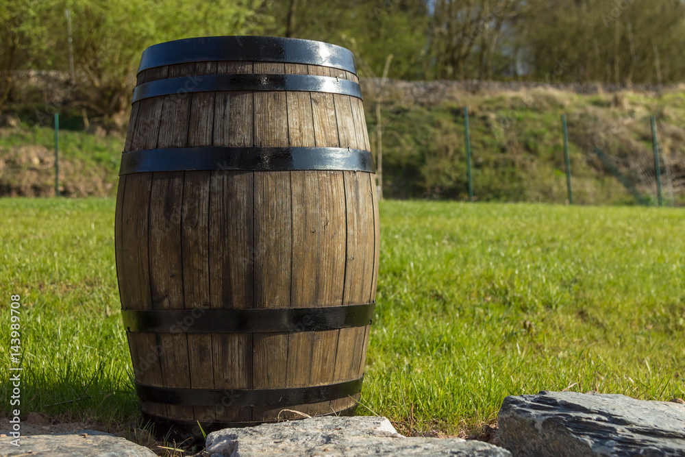 Barrel on some natural stones with a green grass and nice wood as the background