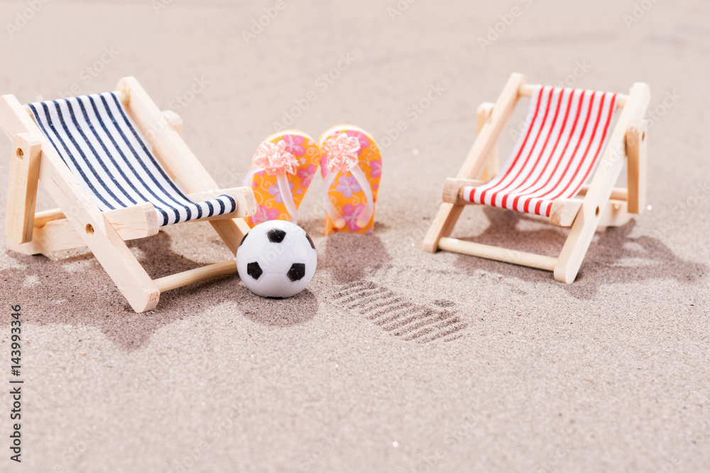 Two empty sun loungers with ball and shoes on the beach Two empty sun loungers with ball and shoes on the beach