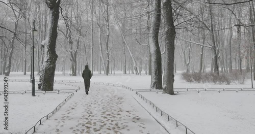 Russia, Saint Petersburg, 26 March 2017: 4k video of Mikhailovsky Garden during a blizzard, walking people, trees, snow, paths, traces photo