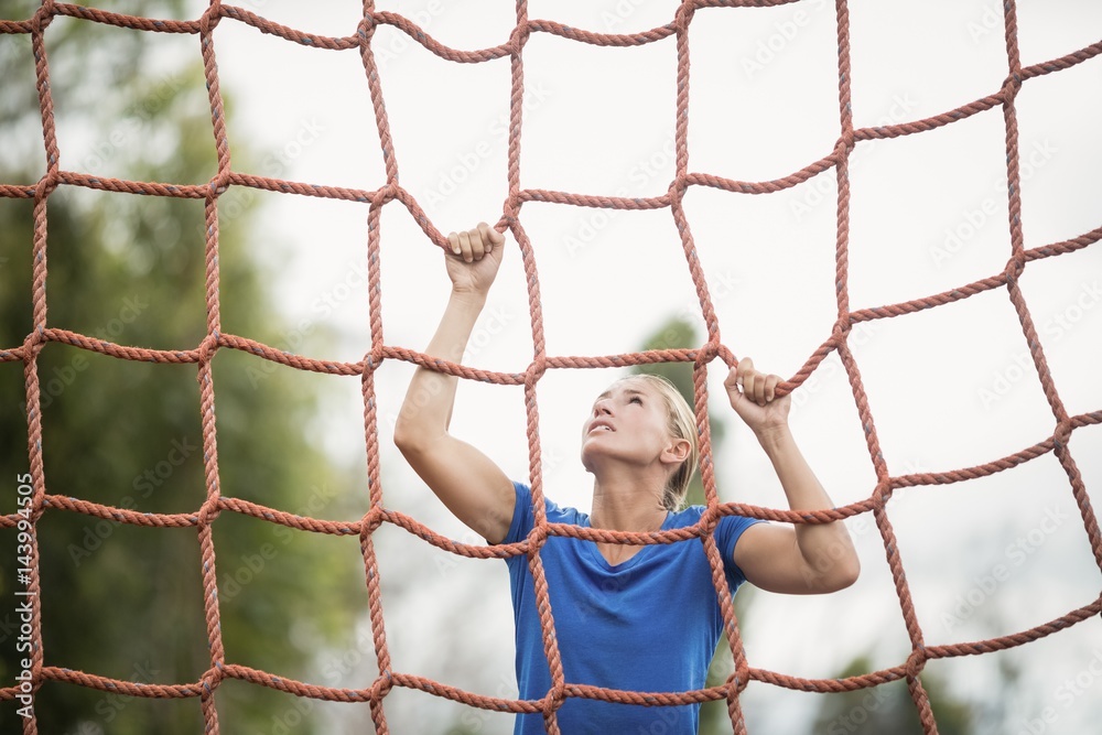 Woman climbing a net during obstacle course Woman climbing a net during obstacle course