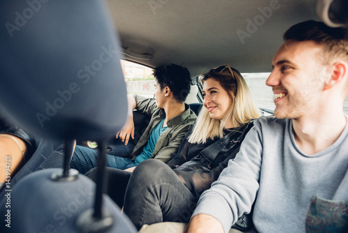 Group of friends multiethnic millennials view from automobile window traveling by car - togetherness, interaction, car sharing concept photo