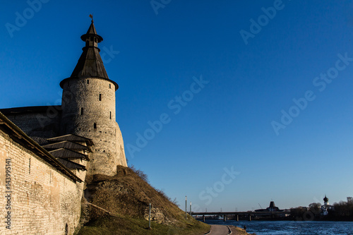 Fortress wall and a tower on the river bank.