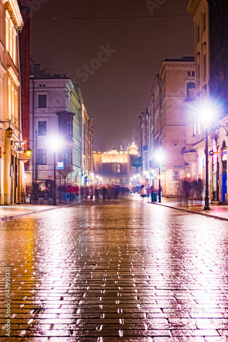 Night street in the Krakow, Poland. Colorful night illumination reflecting in the wet stone pavement of the old town. Beautiful background photo. © romas_ph