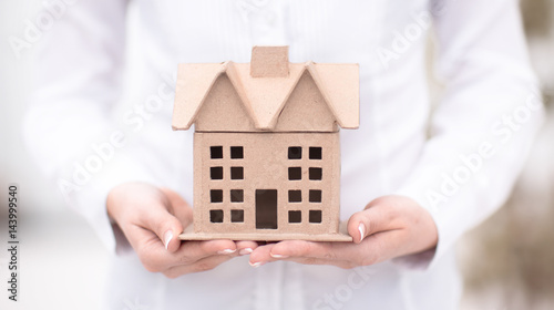 Real estate concept - a woman is holding an architectural model of a house