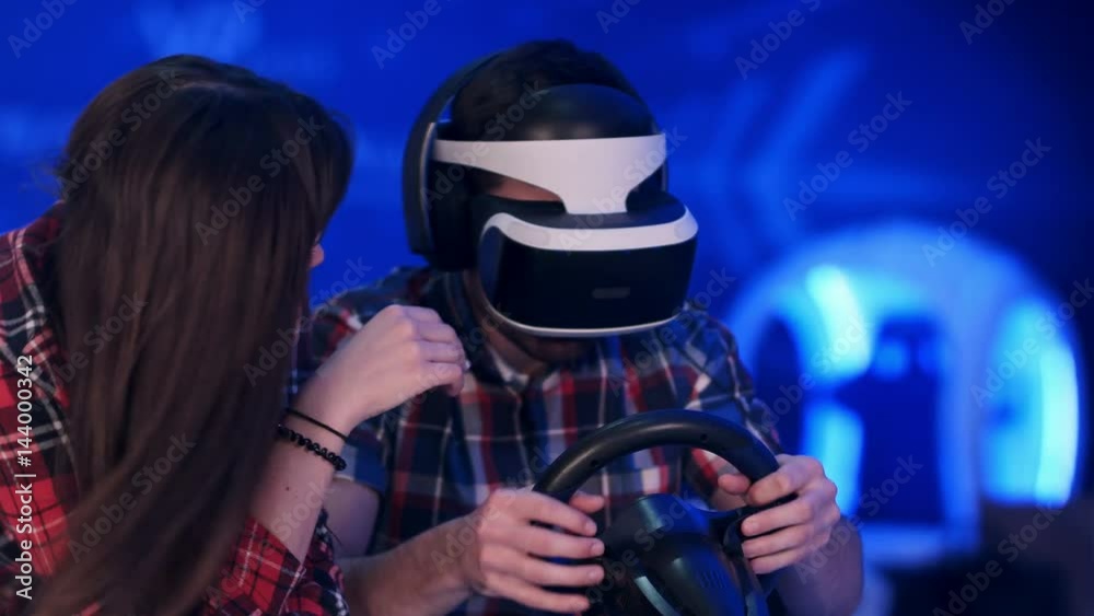 Bored girl trying to distract her boyfriend from playing virtual reality racing game Bored girl trying to distract her boyfriend from playing virtual reality racing game