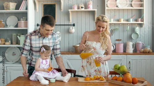 Family eating healthy breakfast in kitchen, happy family mom mother and dad father with little girl child morning with fresh fruits and juices photo