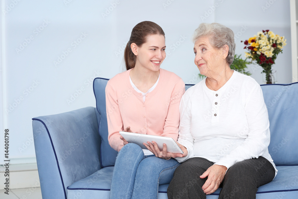 Grandmother and granddaughter with tablet on sofa