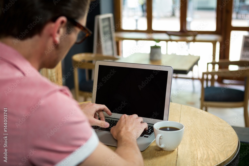 Man using laptop at table in coffee shop
