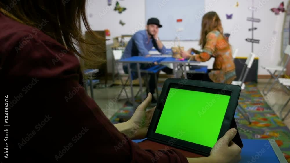 Teenagers in classroom socializing with green screen tablet pc Teenagers in classroom socializing with green screen tablet pc