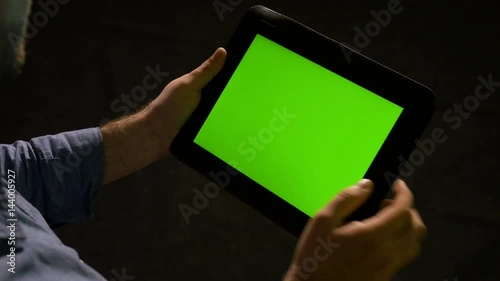 Man using tablet pc with green screen and zooming in and out on the display