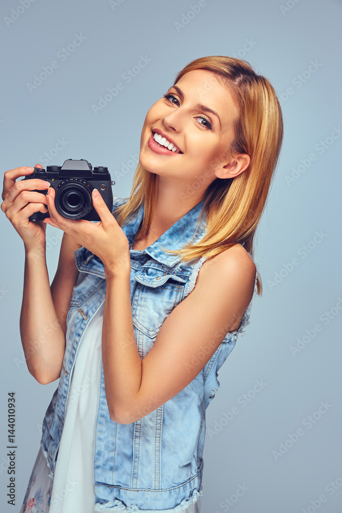 Smiling blond female holds compact digital photo camera. Smiling blond female holds compact digital photo camera.