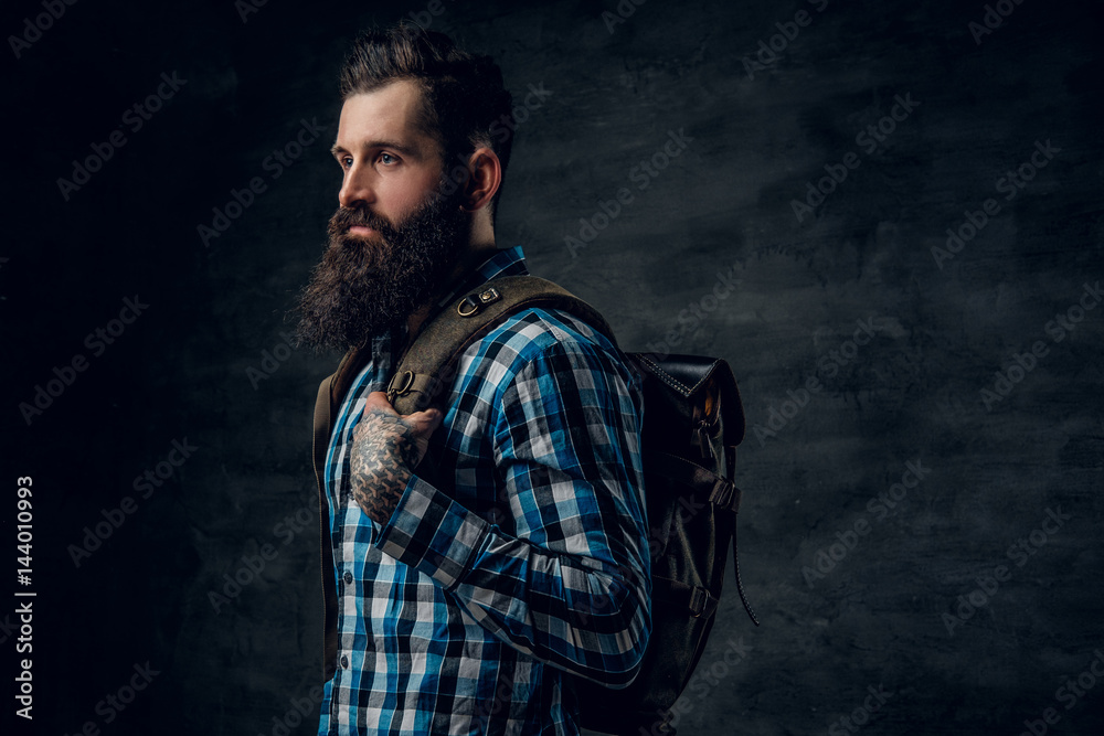 Bearded male with tattoo on arm, dressed in a blue fleece shirt holds backpack. Bearded male with tattoo on arm, dressed in a blue fleece shirt holds backpack.