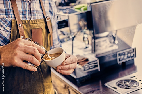 A man preparing cappuccino in a coffee shop.
