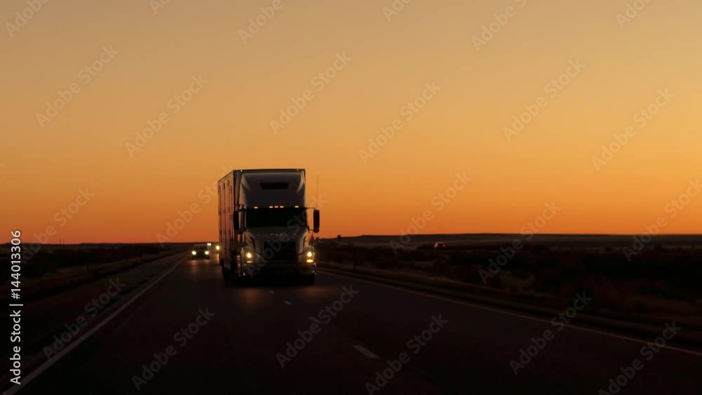 CLOSE UP: Freight container semi trailer truck transporting goods. Cars on road trip driving along the beautiful country highway after the sunset. Lorry shipping cargo, people traveling by night