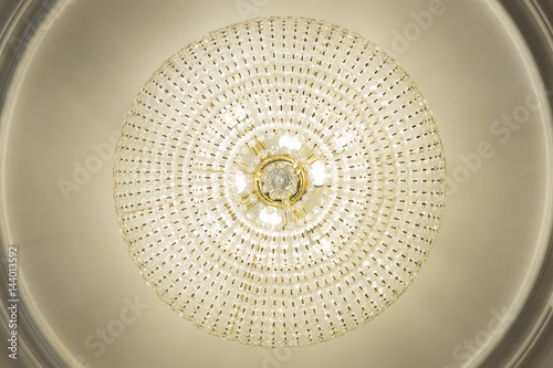 Large electric chandelier made of glass beads on a white decorative ceiling decorated with stucco molding