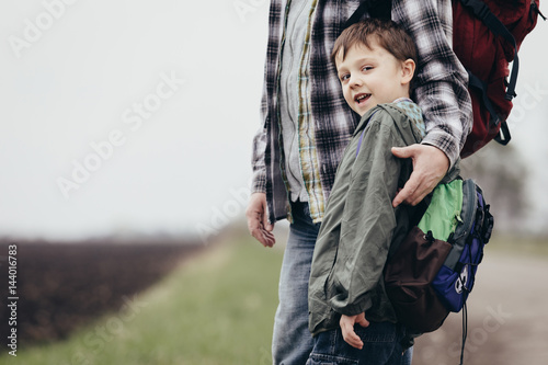 Father and son walking on the road at the day time.