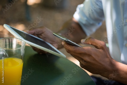 Man holding mobile phone and digital tablet at restaurant