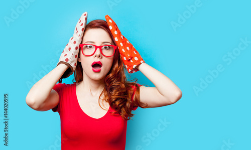 photo of beautiful young woman with potholders on the wonderful blue studio background