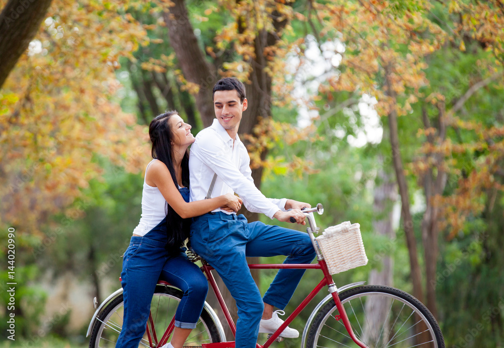 photo of cute couple sitting on bicycle and hugging on the wonderful autumn park background photo of cute couple sitting on bicycle and hugging on the wonderful autumn park background